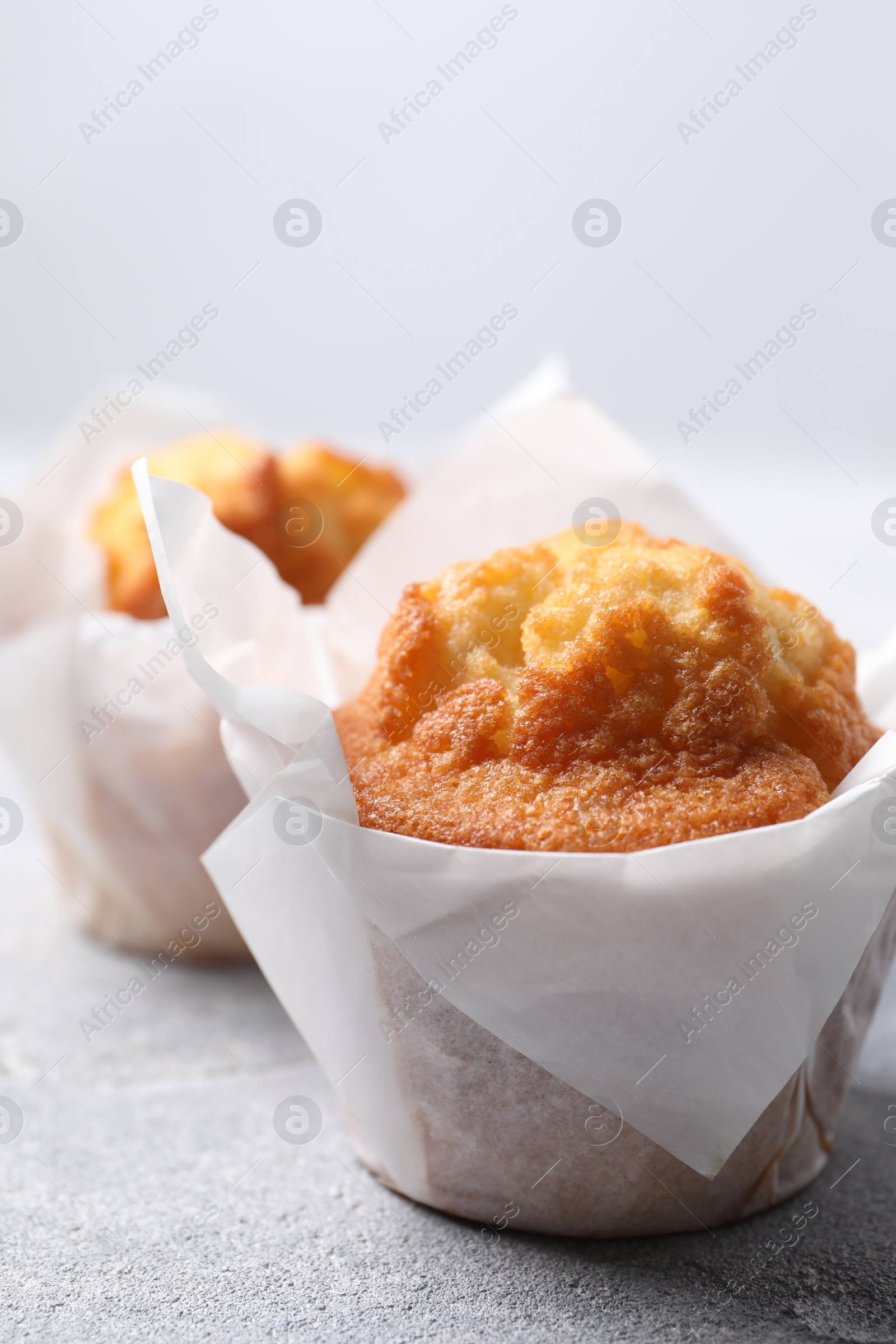 Photo of Delicious sweet muffins on light grey textured table, closeup. Space for text