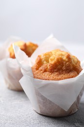 Photo of Delicious sweet muffins on light grey textured table, closeup. Space for text