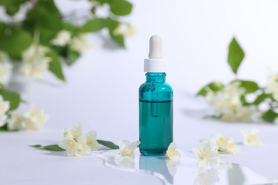 Photo of Essential oil in bottle and beautiful jasmine flowers on white background