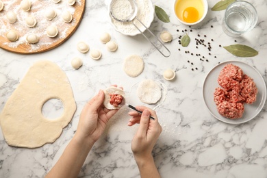 Woman cooking dumplings over marble table, top view