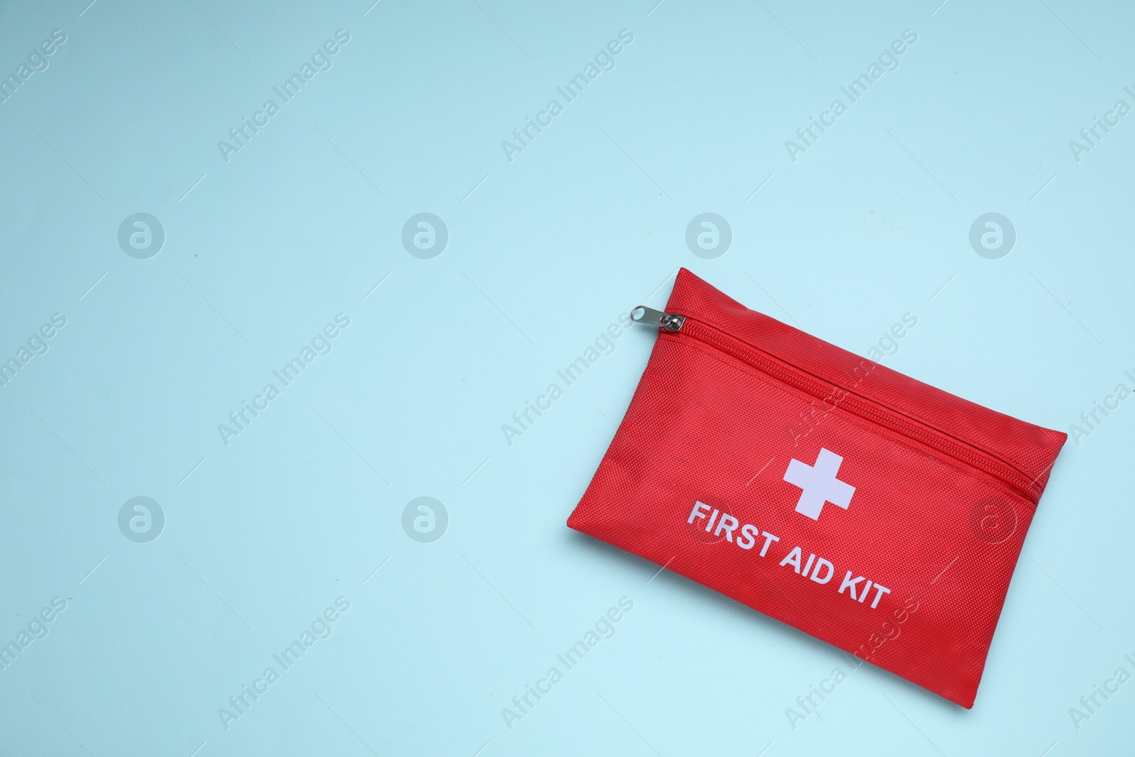 Photo of First aid kit on light blue background, top view and space for text