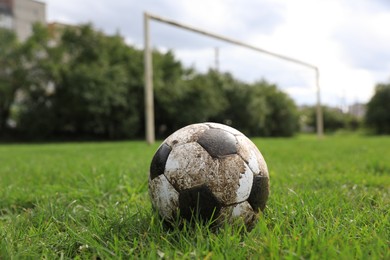Photo of Dirty soccer ball on green grass outdoors