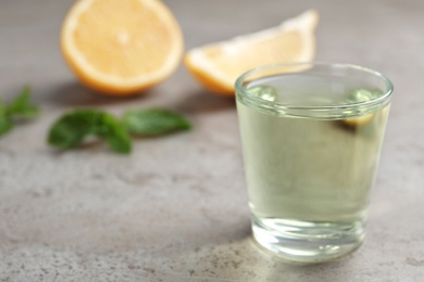 Photo of Glass with mouthwash, lemon and space for text on gray background. Teeth hygiene