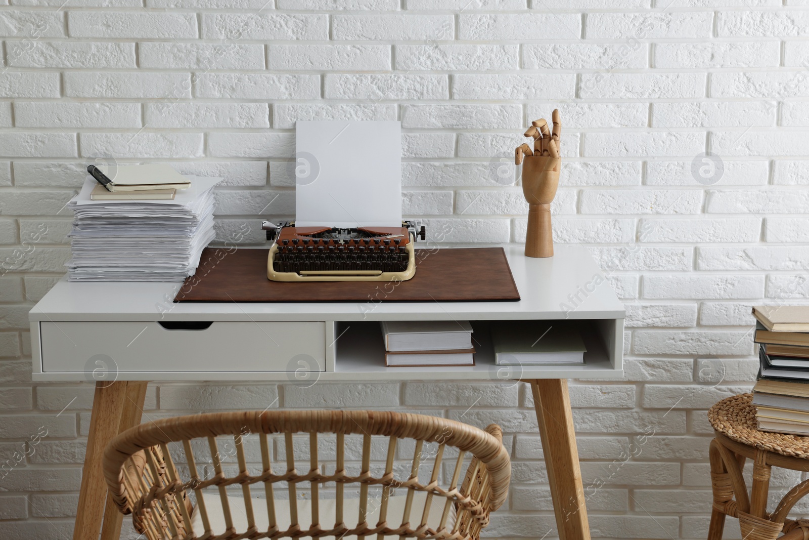 Photo of Comfortable writer's workplace with typewriter on desk near white brick wall