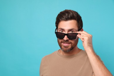 Portrait of bearded man with stylish sunglasses on light blue background. Space for text