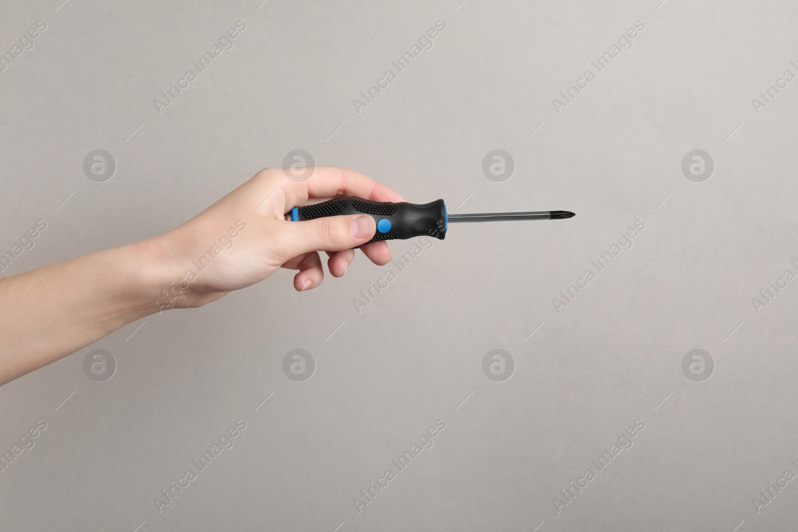 Photo of Woman holding screwdriver on grey background, closeup