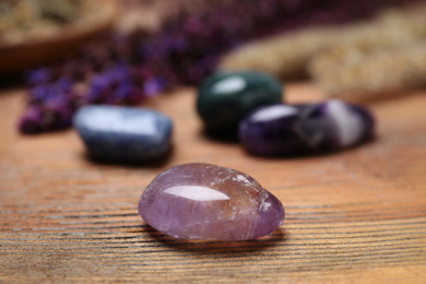 Different gemstones and healing herbs on wooden table, closeup