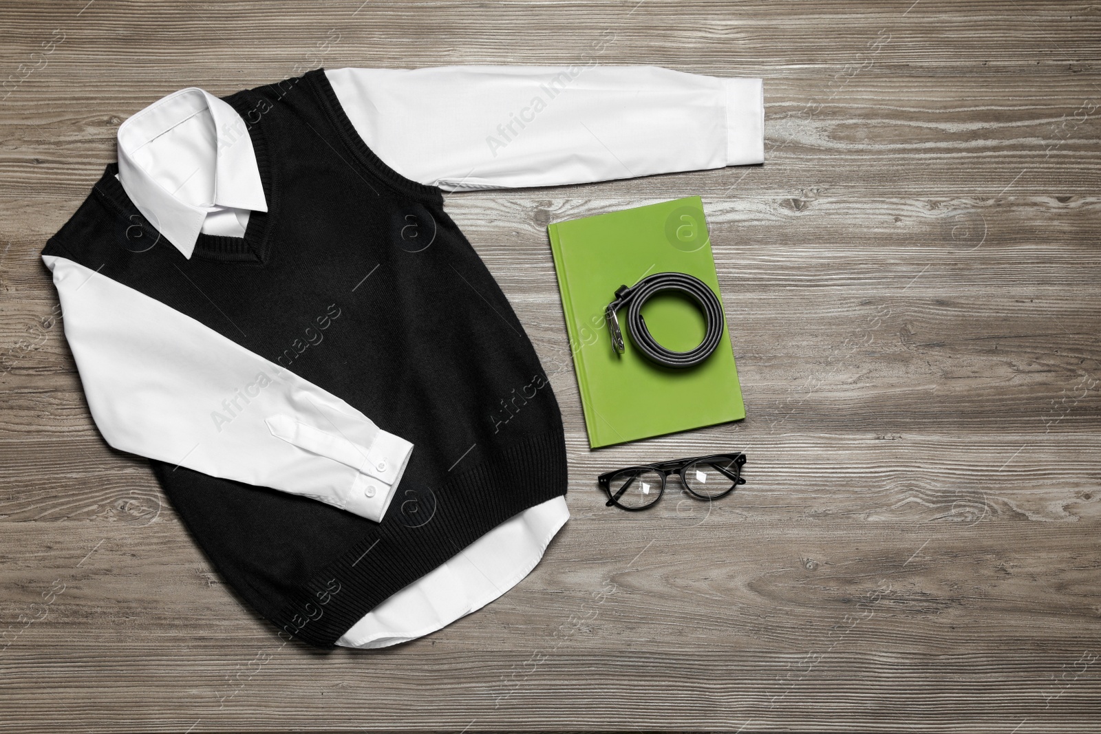 Photo of Stylish school uniform, glasses and notebook on wooden background, flat lay. Space for text