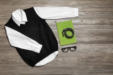 Stylish school uniform, glasses and notebook on wooden background, flat lay. Space for text