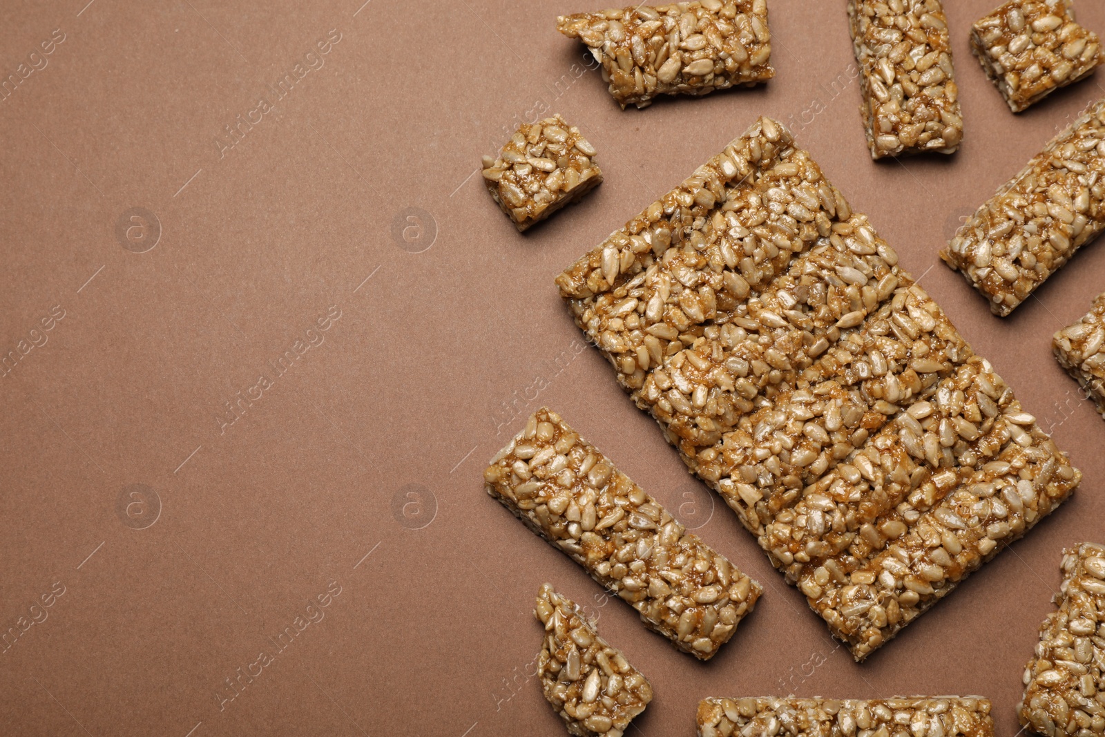 Photo of Pieces of delicious kozinaki bars on brown background, flat lay. Space for text