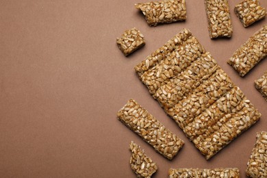 Photo of Pieces of delicious kozinaki bars on brown background, flat lay. Space for text