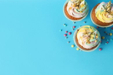 Photo of Cute sweet unicorn cupcakes on light blue background, flat lay. Space for text