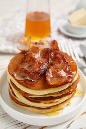 Photo of Delicious pancakes with maple syrup and fried bacon on white wooden table, closeup
