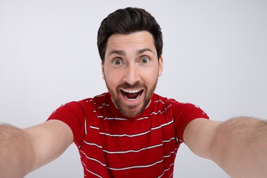 Photo of Smiling man taking selfie on white background