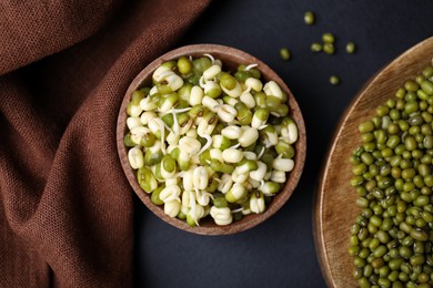 Photo of Wooden bowl with sprouted green mung beans on black background, flat lay