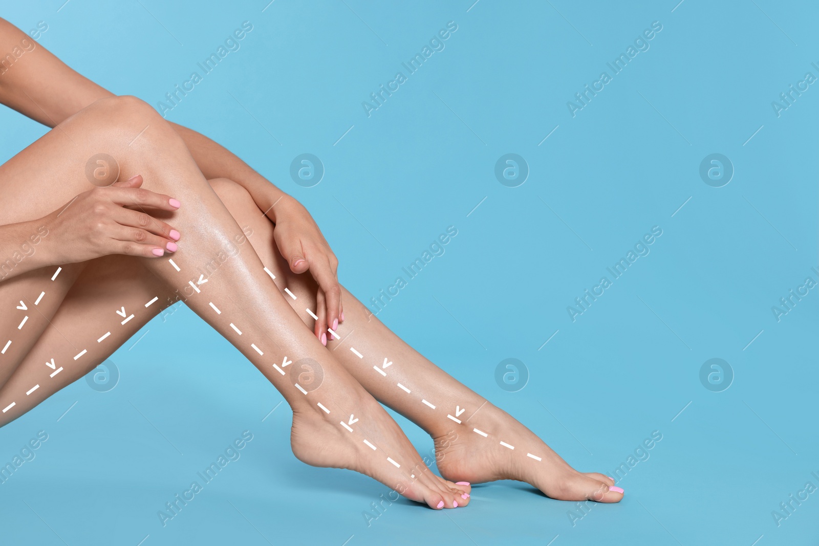 Image of Epilation guide - how to remove hair in proper direction. Woman with drawn lines and arrows on her beautiful smooth legs against light blue background