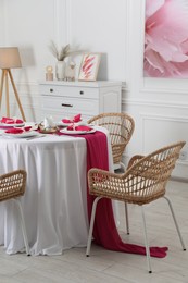 Photo of Color accent table setting. Plates, cutlery and pink napkins in dining room