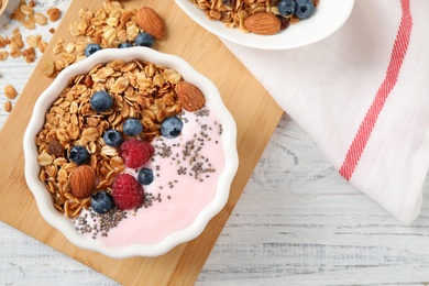 Tasty homemade granola served on white wooden table, flat lay. Healthy breakfast