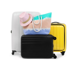 Photo of New suitcases, bag and hat packed for journey on white background