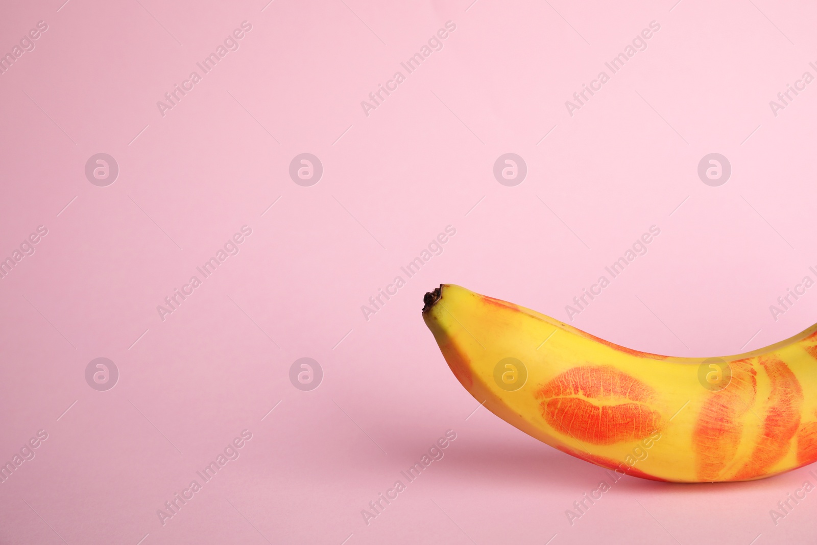 Photo of Fresh banana with red lipstick marks on pink background, space for text. Oral sex concept