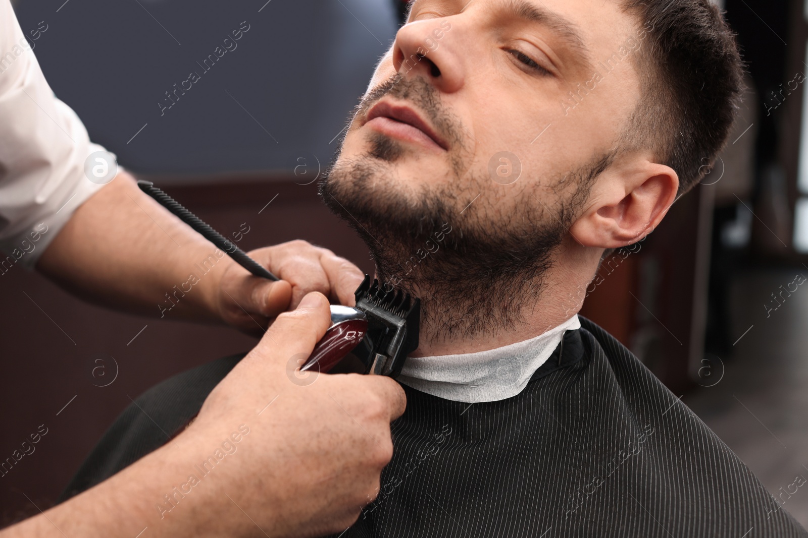 Photo of Professional hairdresser working with client in barbershop, closeup