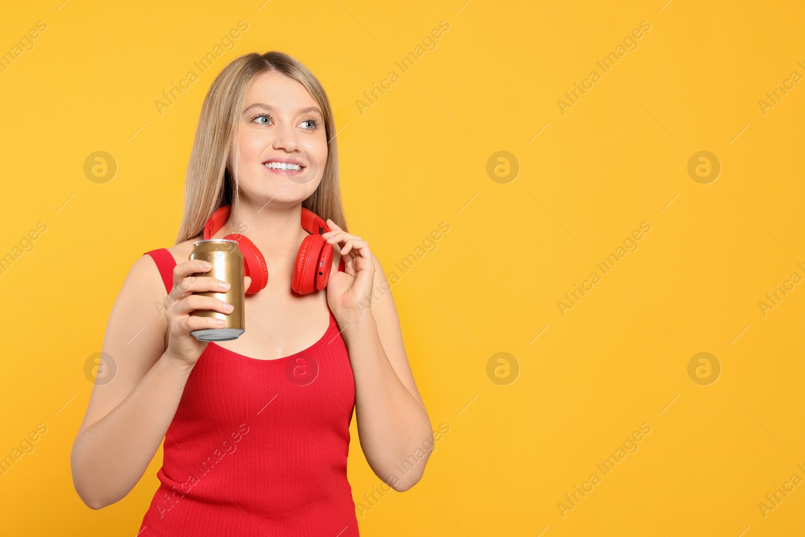 Photo of Beautiful happy woman holding beverage can on yellow background. Space for text