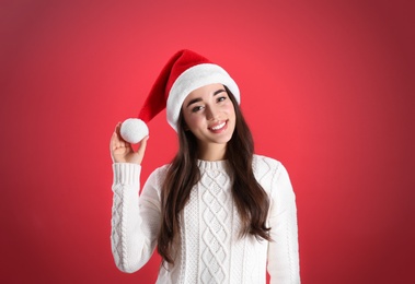 Beautiful woman wearing Santa Claus hat on red background