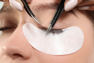 Young woman undergoing eyelash extension procedure, closeup