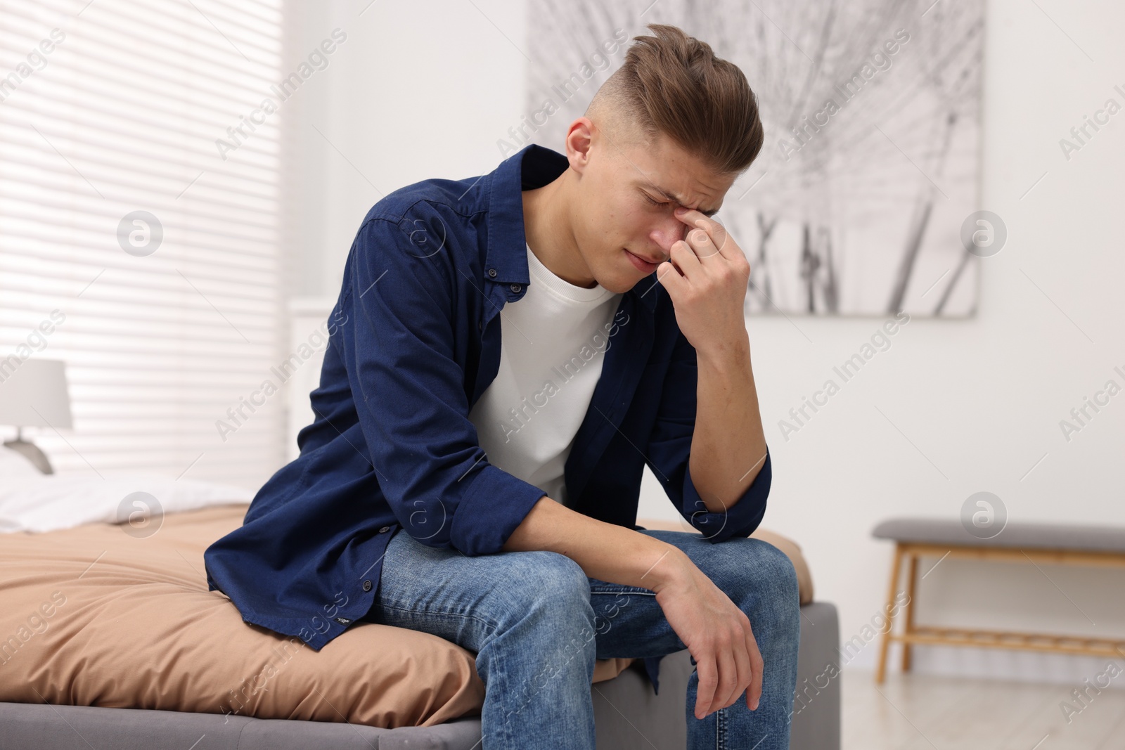 Photo of Overwhelmed man sitting on bed at home