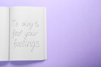 Photo of Notebook with phrase It`s Okay to Feel Your Feelings on violet background, top view. Space for text