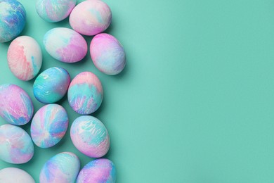 Photo of Many decorated Easter eggs on turquoise background, flat lay. Space for text