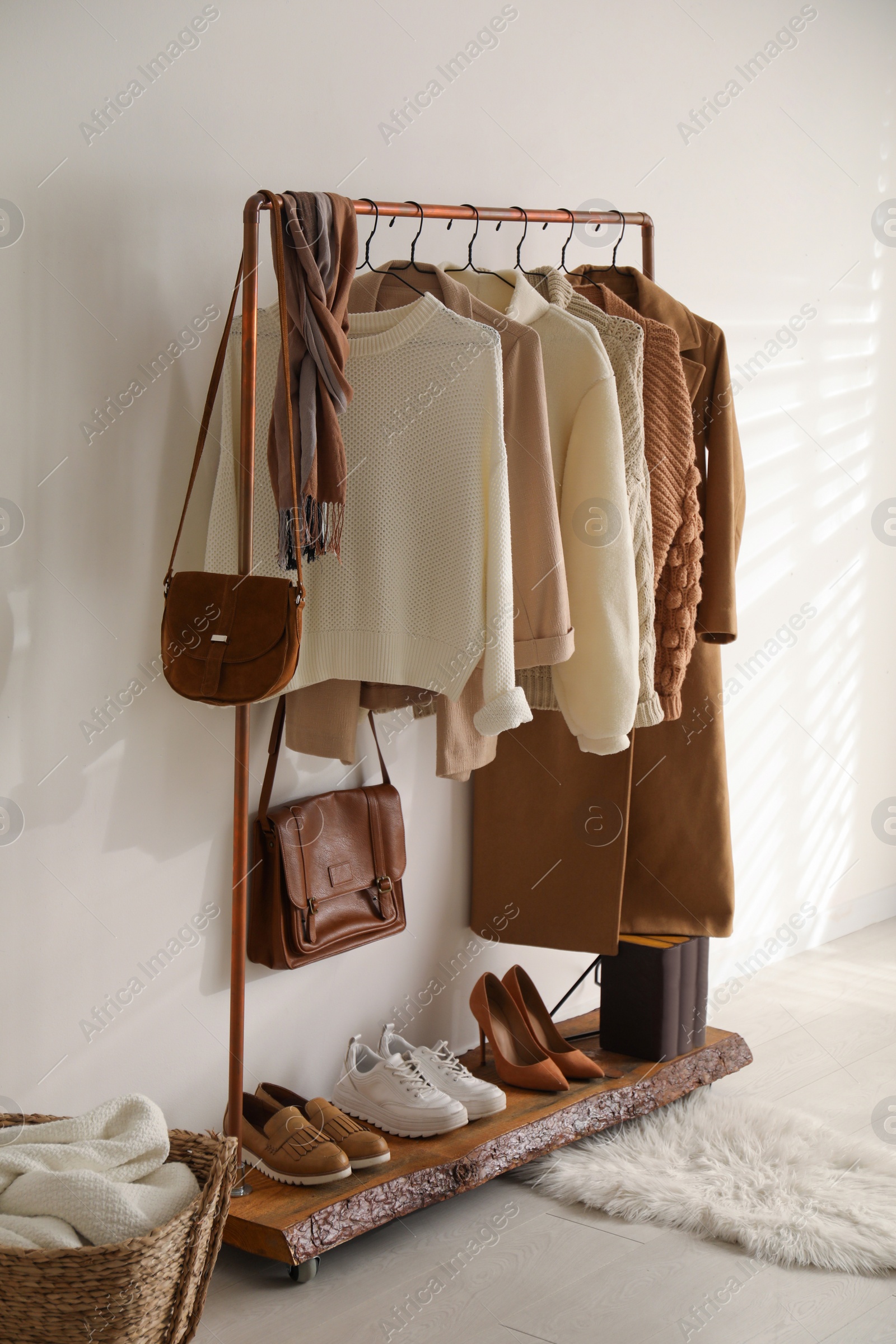 Photo of Rack with stylish shoes and women's clothes in dressing room. Modern interior design