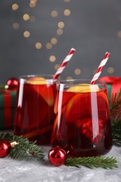 Photo of Delicious Sangria drink in glasses and Christmas decorations on grey textured table, closeup