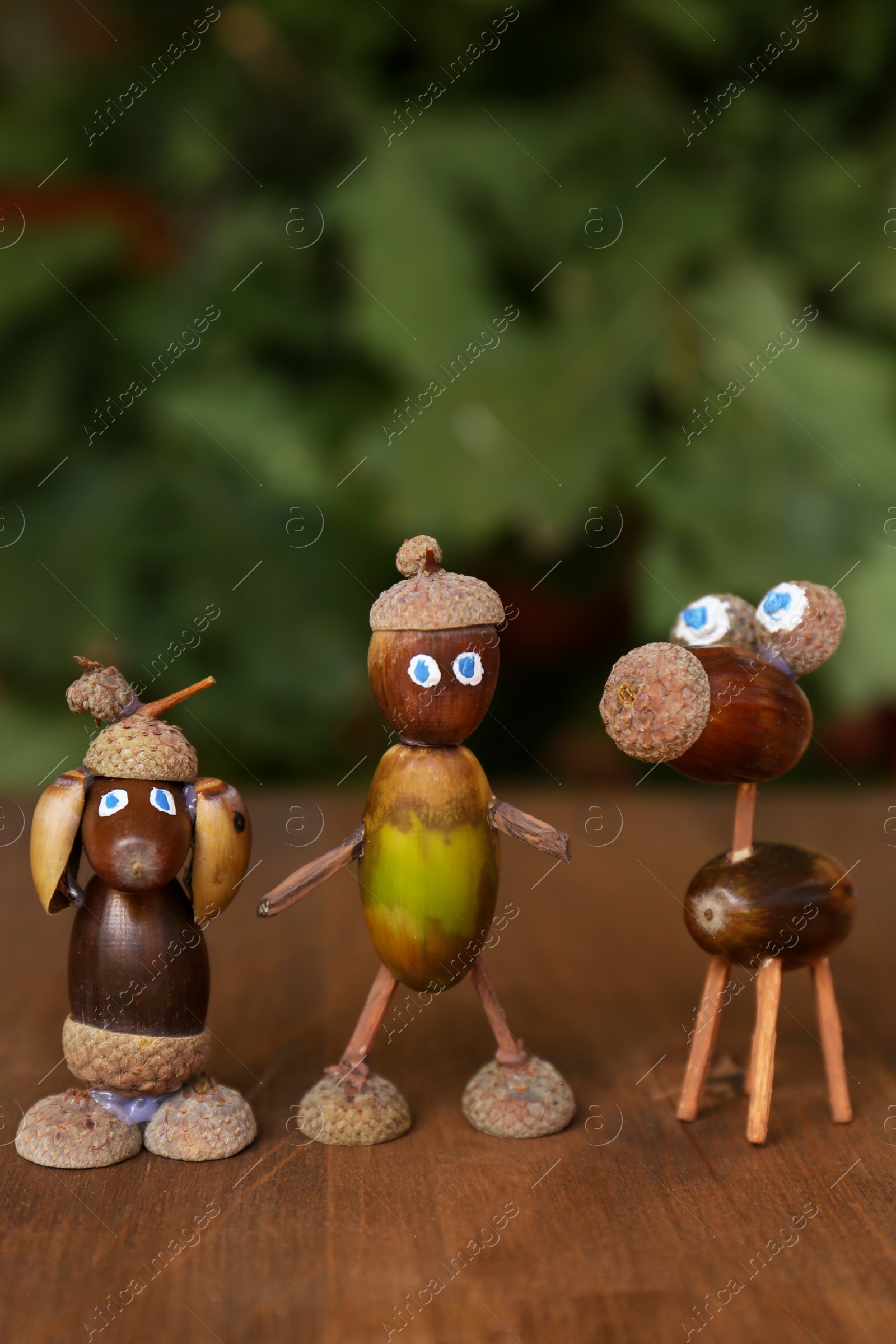 Photo of Cute figures made of acorns on wooden table