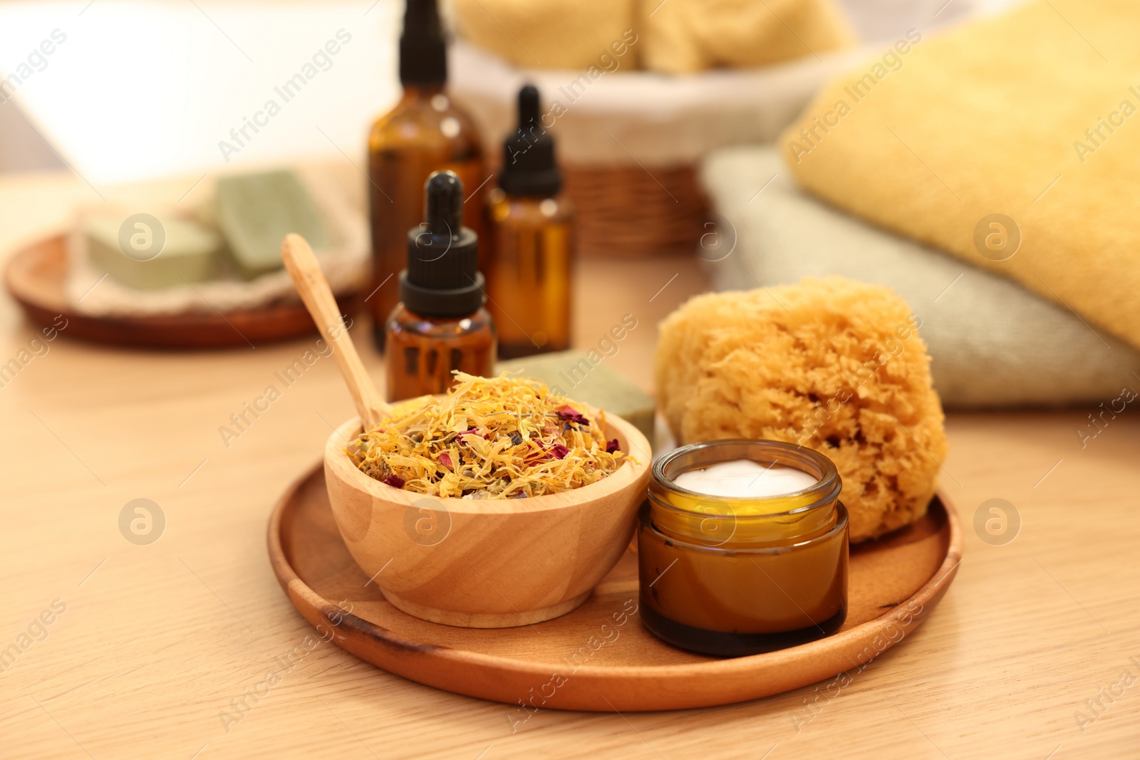 Photo of Dry flowers, loofah and jar with cream on wooden table. Spa time