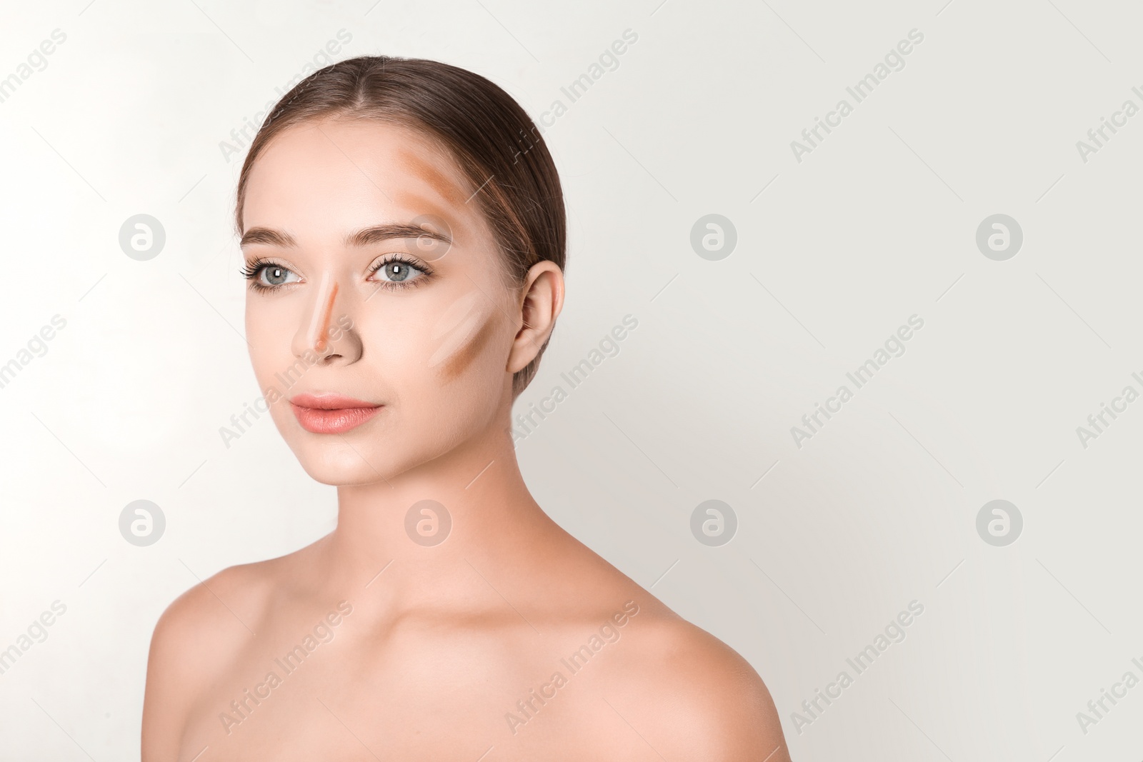 Photo of Portrait of beautiful young woman with makeup contouring smears on face against white background