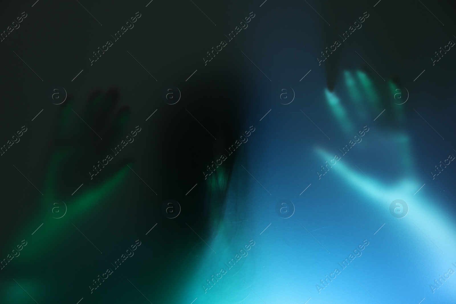 Photo of Silhouette of creepy ghost behind glass against color background