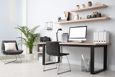 Photo of Modern computer on table in office interior. Stylish workplace