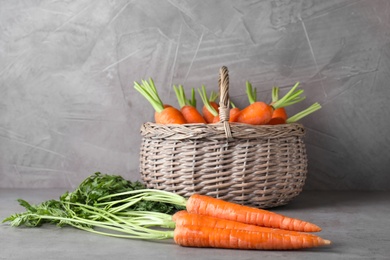 Photo of Basket with fresh carrots on grey background
