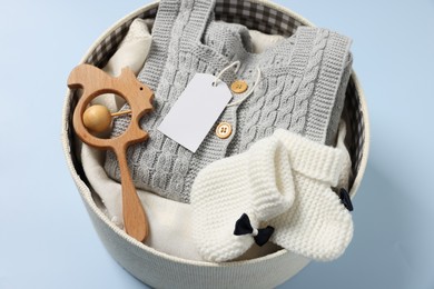 Different baby accessories and clothes in box on light blue background, above view