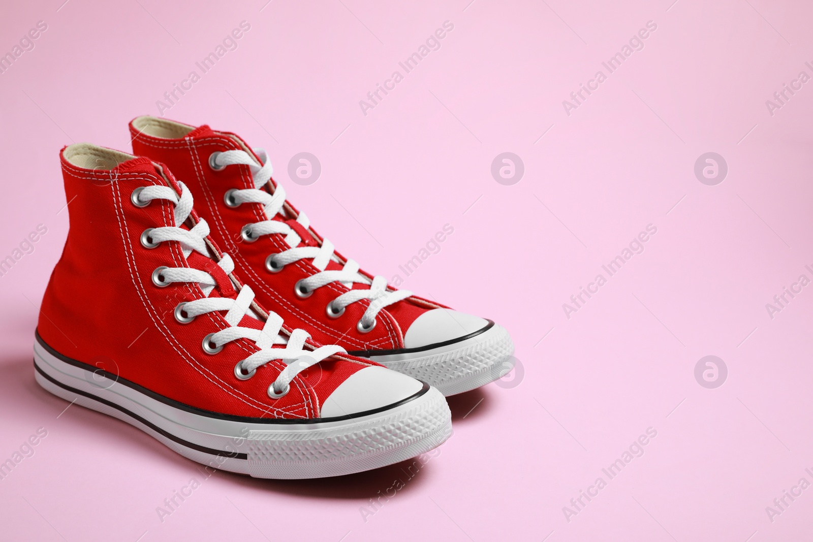 Photo of Pair of new stylish red sneakers on pink background. Space for text