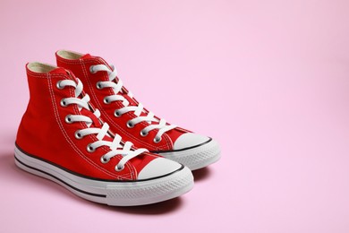 Photo of Pair of new stylish red sneakers on pink background. Space for text