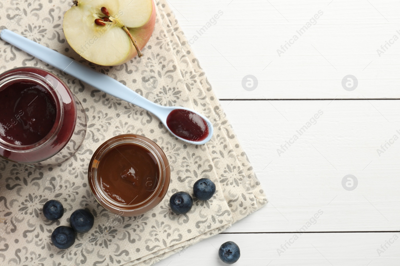 Photo of Tasty baby food in jars and ingredients on white wooden table, flat lay. Space for text