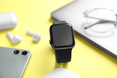 Photo of Composition with stylish smart watch on yellow background, closeup