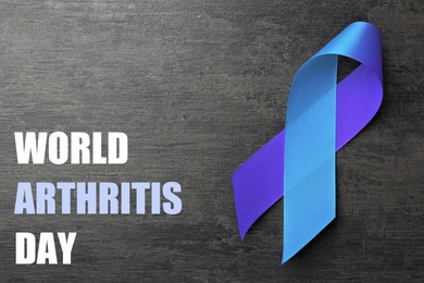 Image of World Arthritis Day. Blue and purple awareness ribbon on dark grey background, top view