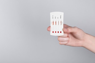 Photo of Woman holding disposable multi-infection express test on light grey background, closeup. Space for text