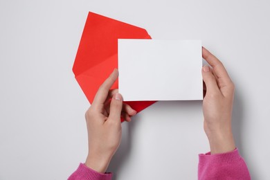 Photo of Woman with blank card and letter envelope at white table, top view. Space for text