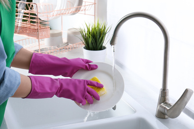 Woman washing plate in modern kitchen, closeup