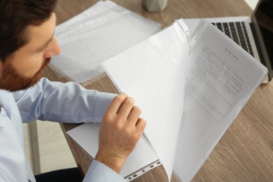 Businessman working with documents at wooden table in office, closeup