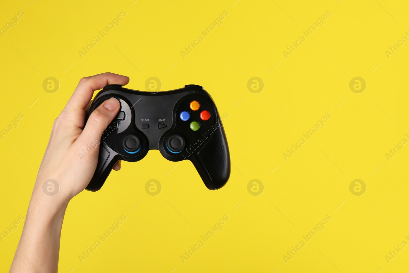 Photo of Woman using game controller on yellow background, closeup. Space for text